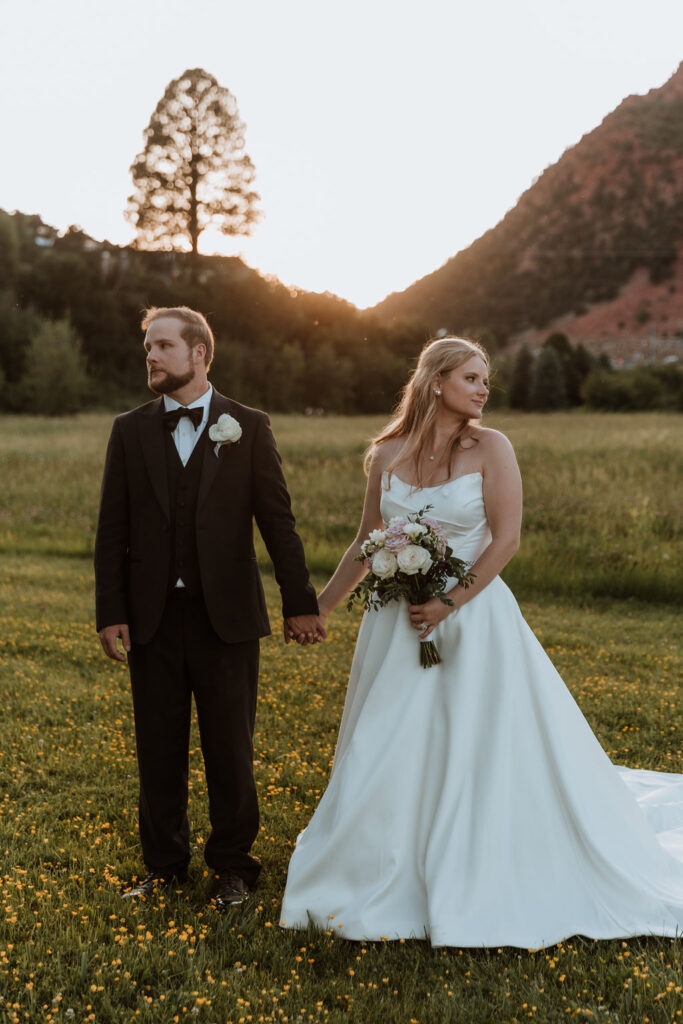 couple hold hands looking in opposite directions 