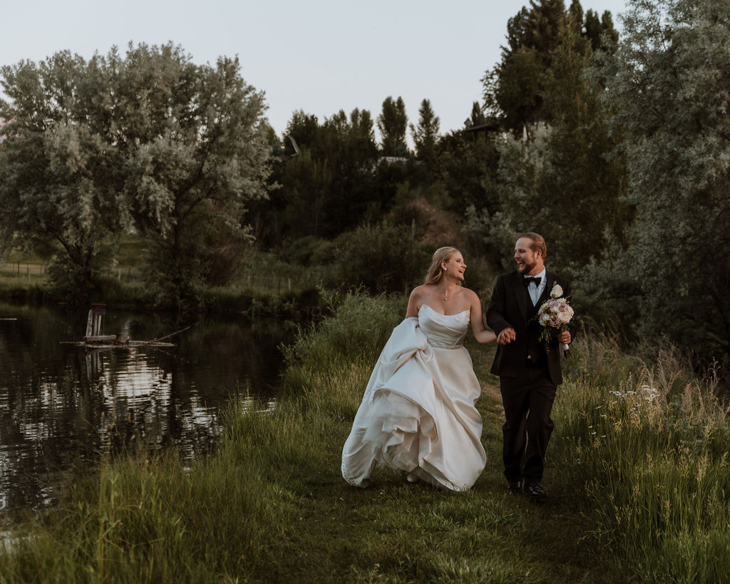 couple running along grassy path and pond at Spring Creeks Ranch