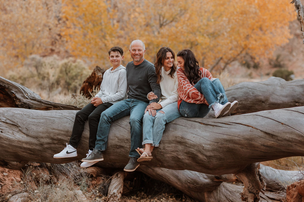 family sits together on large fallen tree trunk