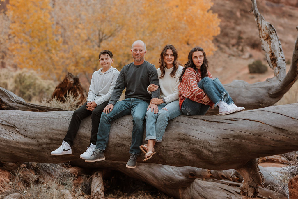 family sits together on large fallen tree trunk