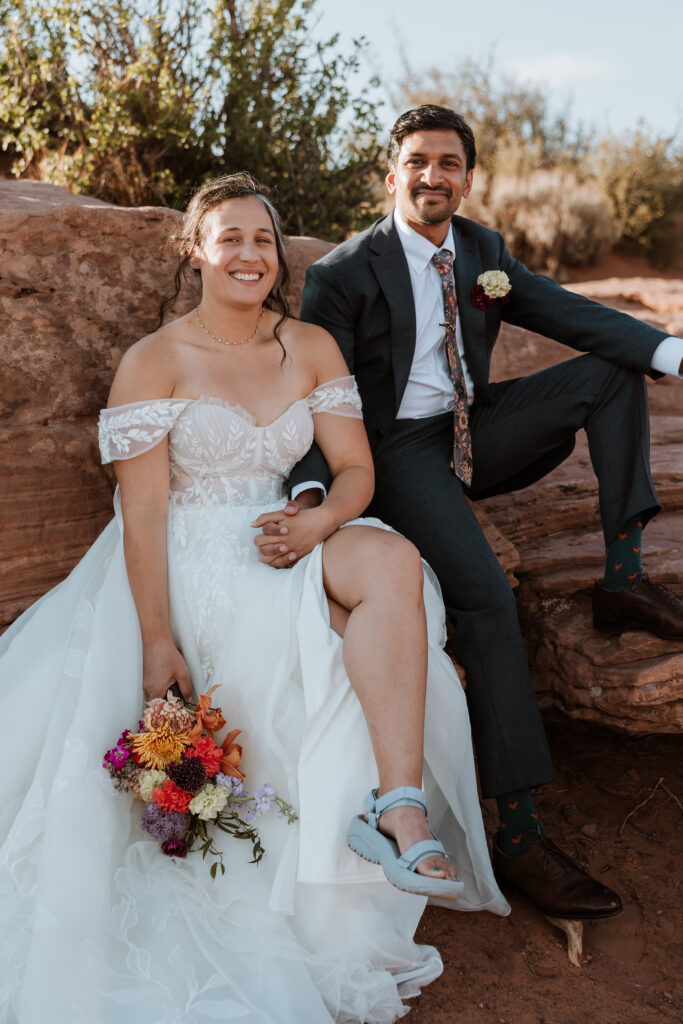 couple pose while sitting on rock