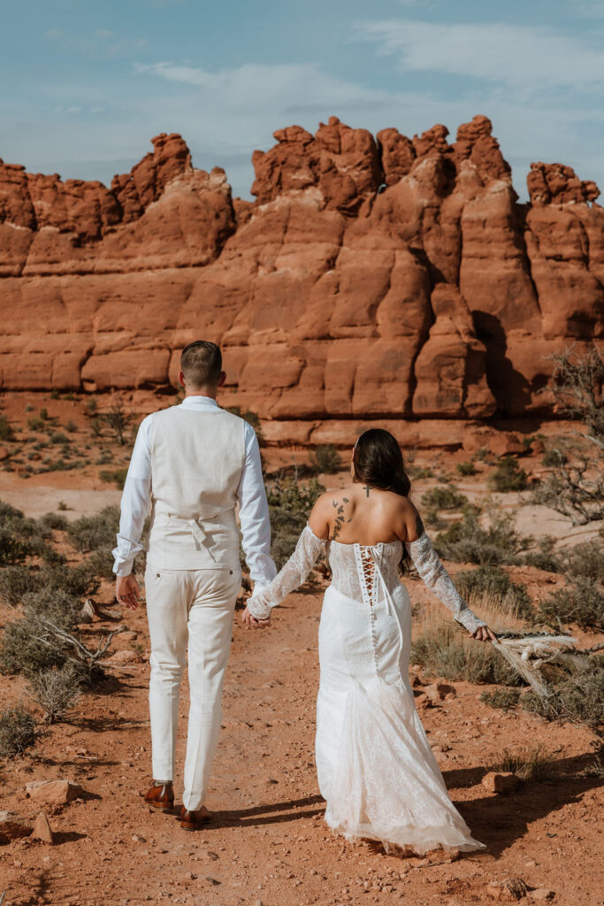 couple walks together holding hands along Moab hiking trails