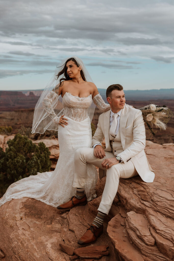 couple poses on rock structure overlooking Moab