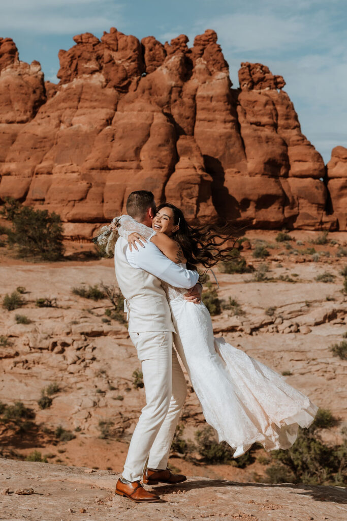 couple embrace in front of large rock structure