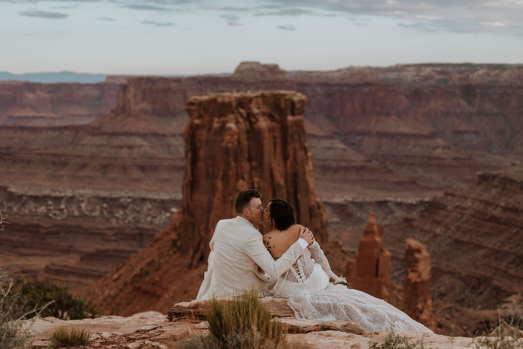 couple kiss while overlooking Moab landscape