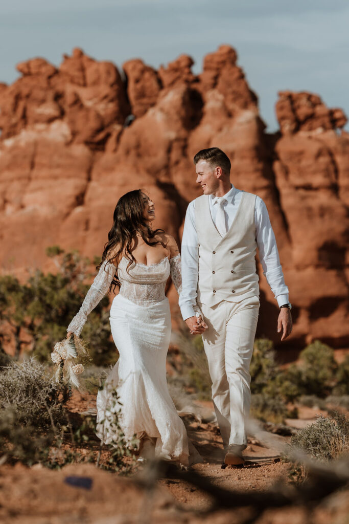 couple walks together holding hands along Moab hiking trails