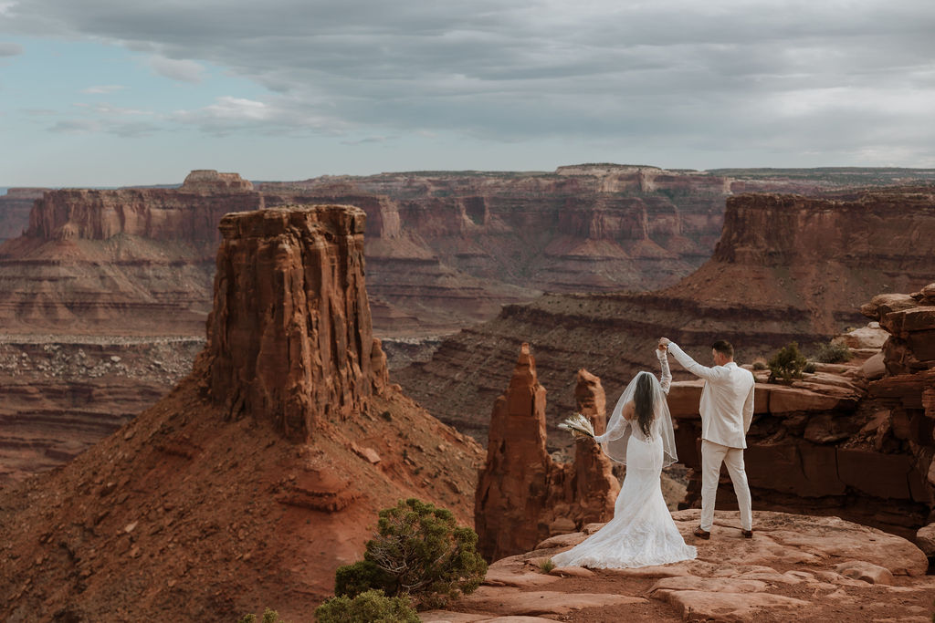 couple holds hands while overlooking Moab landscape
