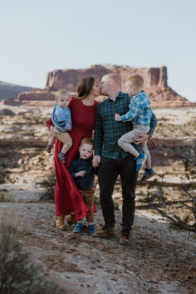 couple kiss while taking photos with family