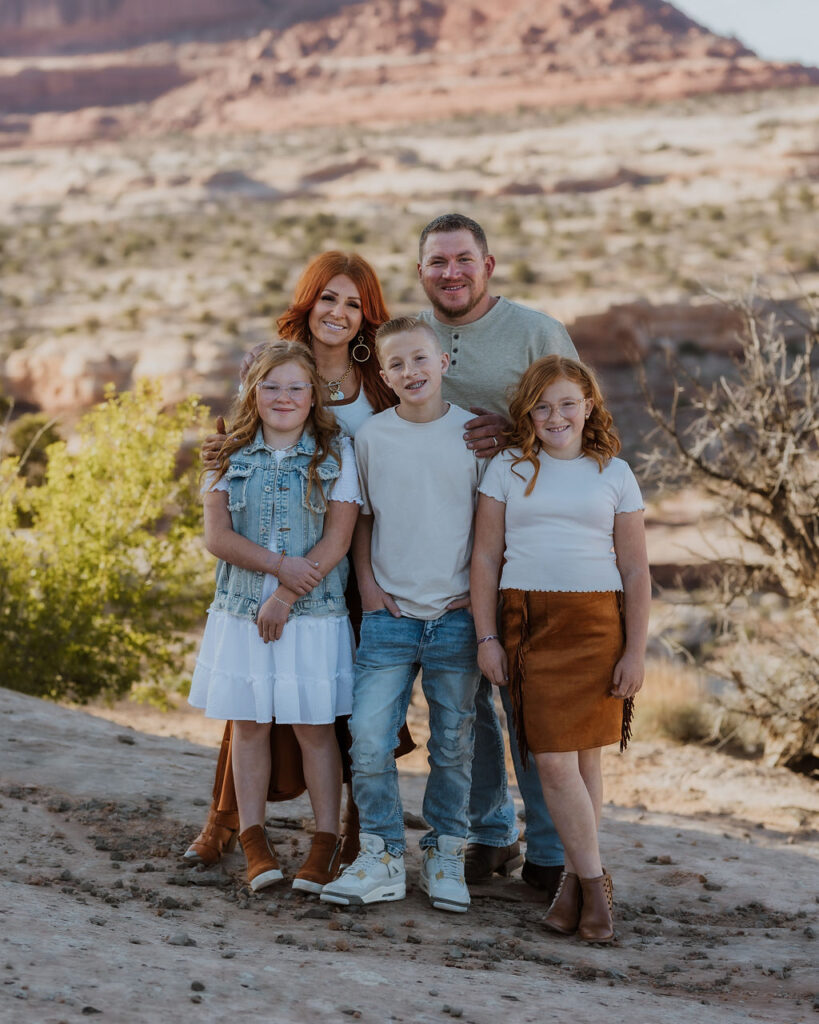 family poses together while walking along one of Moab's hiking trails