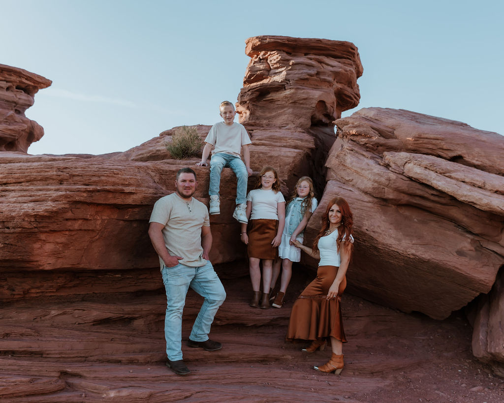 family stops and poses with rock structure along Moab hiking trails