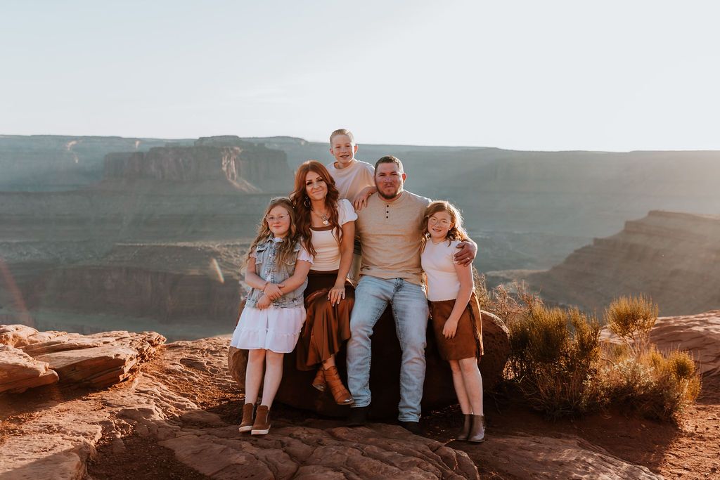 family poses together on rock structure overlooking Moab