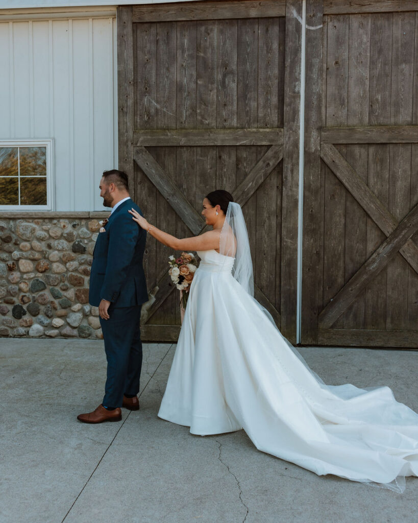 bride touches groom's shoulder during wedding first look