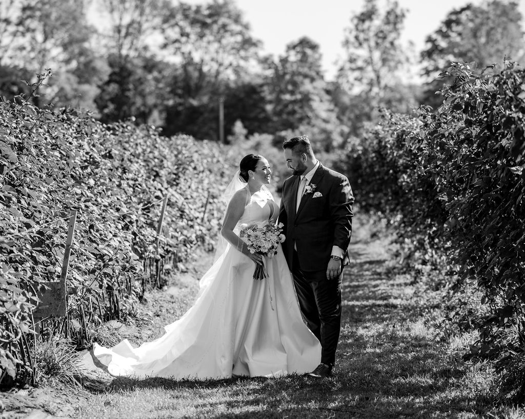couple poses together in a path of the vineyard