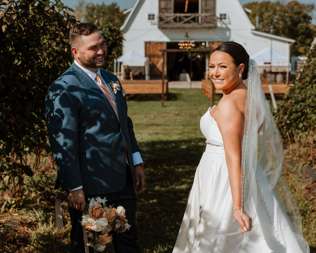 couple pose along path in front of barn