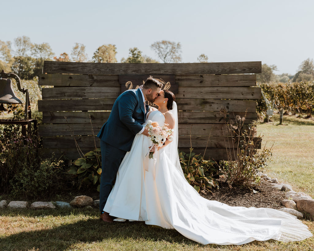 couple kiss in front of wooden sign