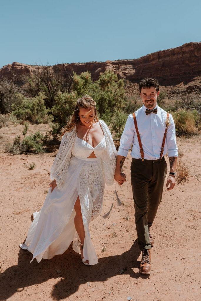 couple walks together holding hands along rocky path